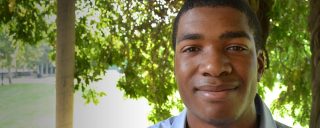 Closeup of Isaiah, a Corning intern, trees, field in background